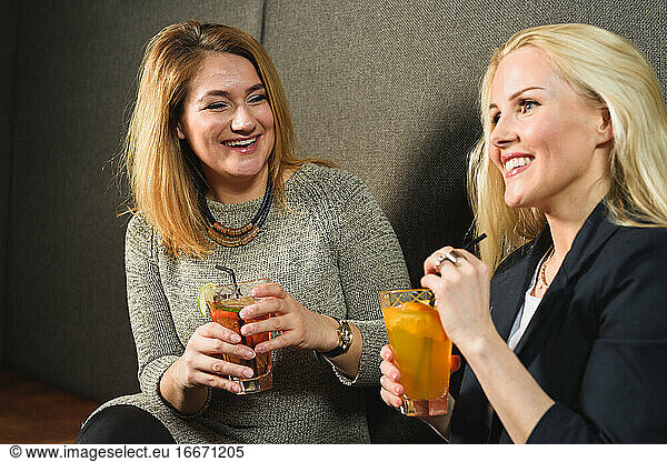 Delighted women enjoying cocktails in pub