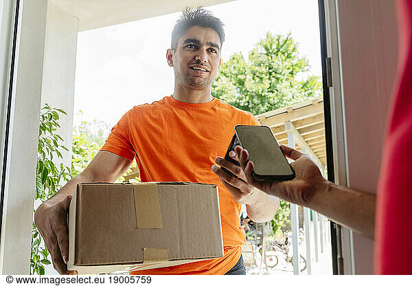 Delivery man holding box taking payment from customer