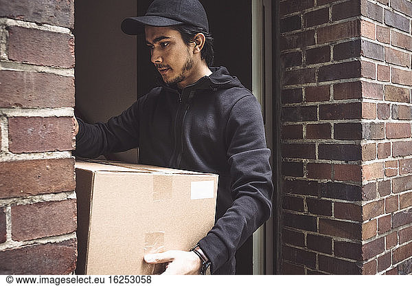 Delivery man with package standing in doorway