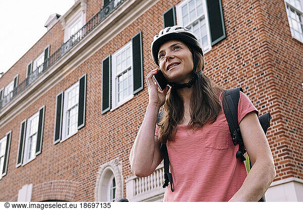Delivery woman talking on smart phone in front of building