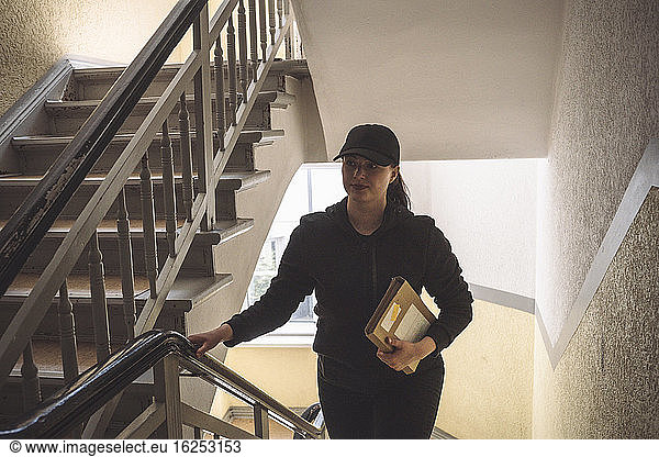 Delivery woman with package climbing staircase