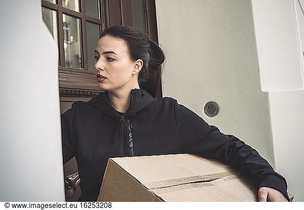 Delivery woman with package standing at doorstep