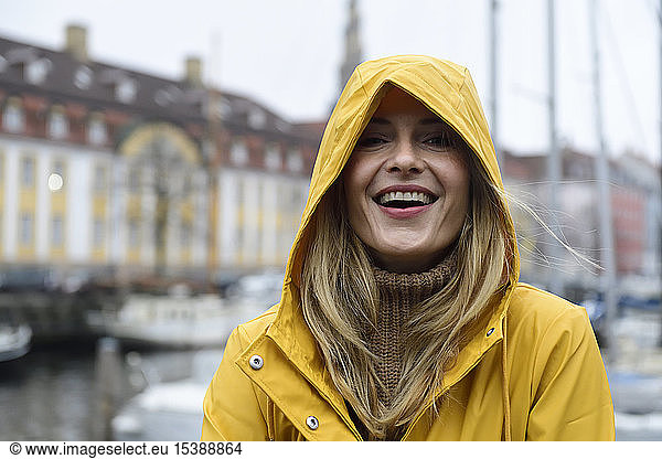 Denmark, Copenhagen, portrait of happy woman at city harbour in rainy weather