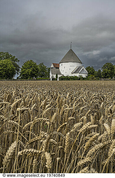 Denmark  Bornholm  Nylars  Storm clouds over field in front of Nylars Church