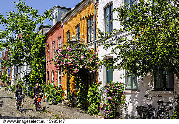 Denmark  Copenhagen  Man and woman riding bicycles along street of historical Nyboder district