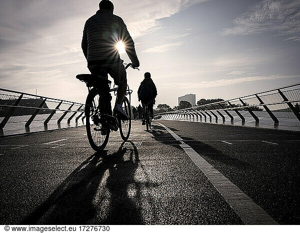 Denmark  Copenhagen  Silhouettes of two people riding bicycles across Langebro bridge at sunset