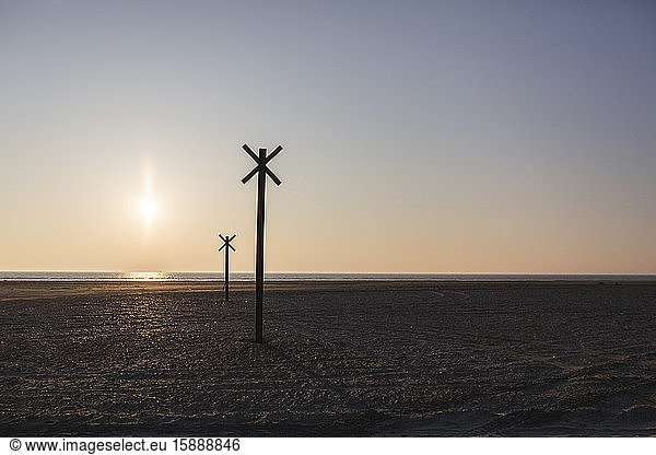 Denmark  Romo  Silhouettes of distance markers on coastal beach at sunset