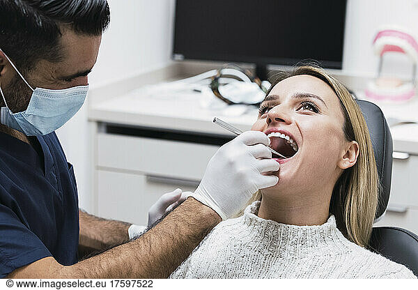 Dentist analyzing patient's teeth in medical room at clinic during COVID-19