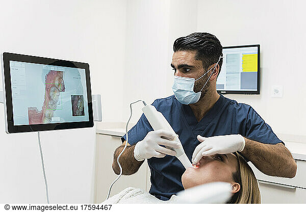 Dentist analyzing patient's teeth on intraoral scanner screen in clinic