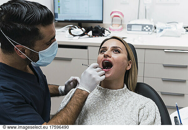 Dentist analyzing patient teeth in clinic