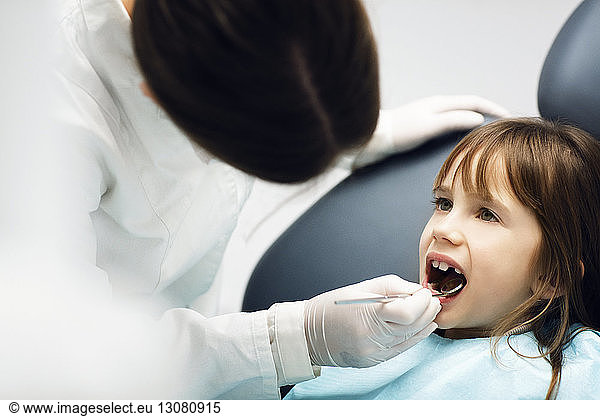 Dentist checking girl's teeth at clinic