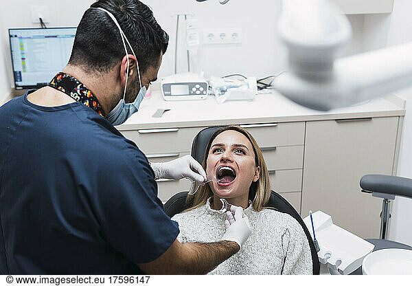 Dentist checking patient's teeth in medical room at clinic