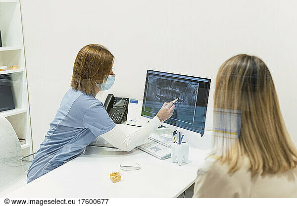 Dentist discussing with patient over intraoral scanner screen sitting at desk