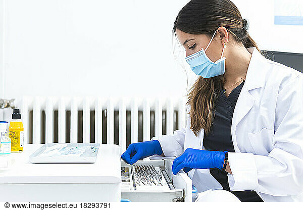 Dentist examining dental tools in drawer at clinic