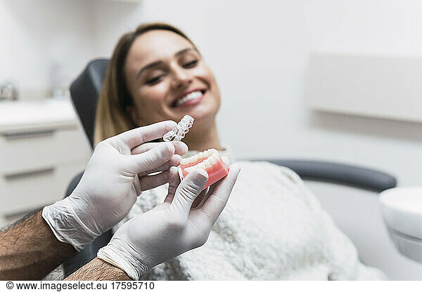 Dentist holding dentures by patient at medical room
