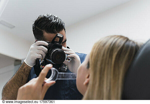 Dentist photographing patient's teeth through camera at medical clinic