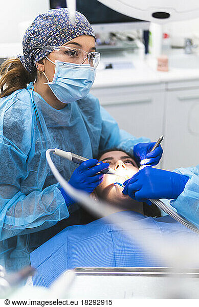 Dentist wearing protective eyewear examining patient in clinic