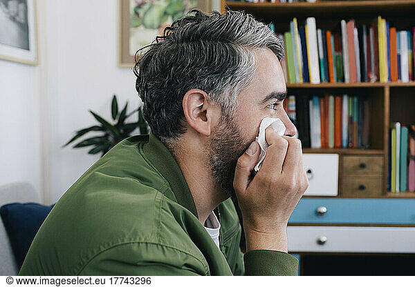 Depressed man rubbing face with tissue paper at therapy office