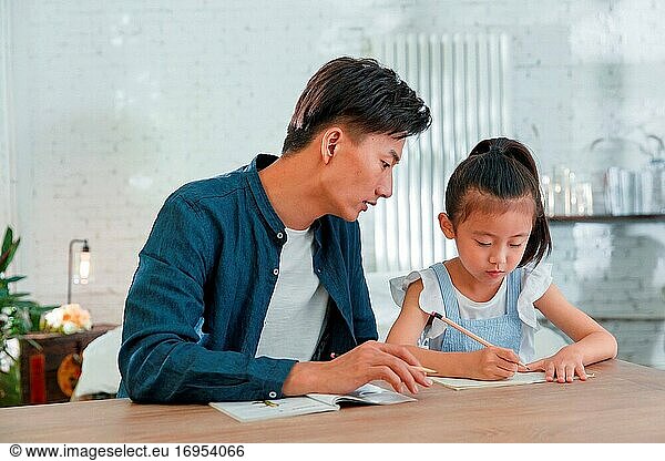 Der junge Mann  der seine Tochter bei den Hausaufgaben betreut