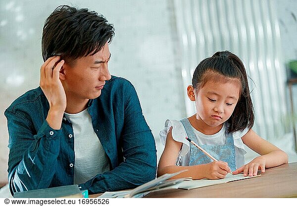 Der junge Mann  der seine Tochter bei den Hausaufgaben betreut