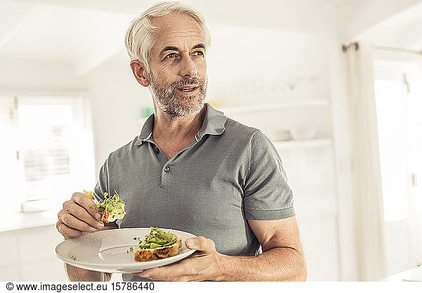 Der reife Mann isst ein gesundes Avocadobrot