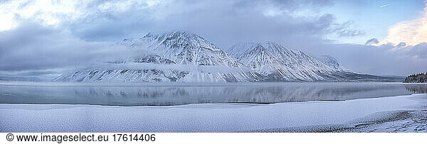 Der schneebedeckte Mount Worthington spiegelt sich in den stillen Wassern des Kathleen Lake wider  wobei neblige  tiefhängende Wolken und blaue Farben eine stimmungsvolle Atmosphäre schaffen; Haines Junction  Yukon  Kanada