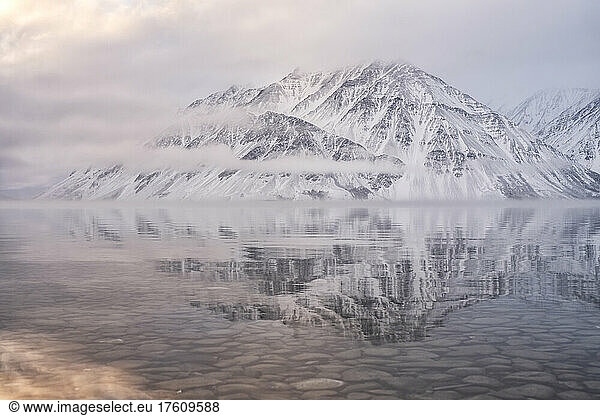 Der schneebedeckte Mount Worthington spiegelt sich in den stillen Wassern des Kathleen Lake  wobei neblige  tiefhängende Wolken und gedämpfte Farben eine stimmungsvolle Atmosphäre schaffen; Haines Junction  Yukon  Kanada