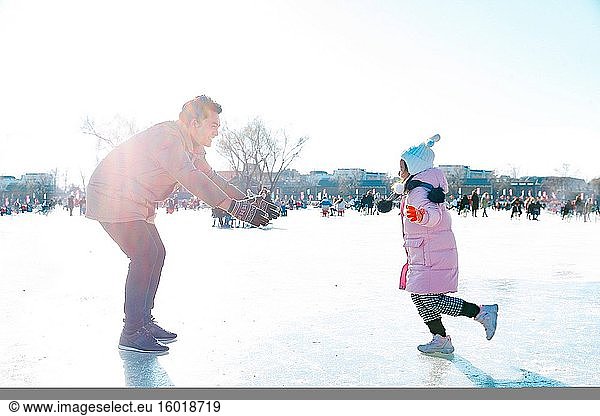 Der Vater und die Tochter spielen auf der Eisbahn