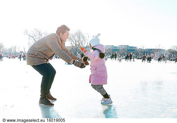 Der Vater und die Tochter spielen auf der Eisbahn