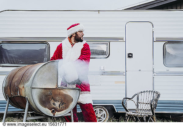 Der Weihnachtsmann bereitet ein Barbecue vor einem Wohnmobil vor