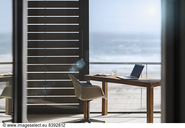 Desk and chair in modern home office overlooking ocean