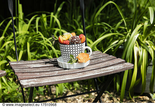 Dessert with energy balls (raw confectionery) and fresh fruits and flowers on garden chair