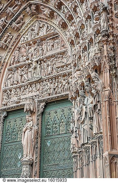 Detail der Tür mit Schnitzereien religiöser Figuren an der Westfassade der Kathedrale Notre Dame in der Stadt Straßburg im Elsass im Osten Frankreichs.