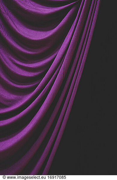 Detail draped purple curtain against black background