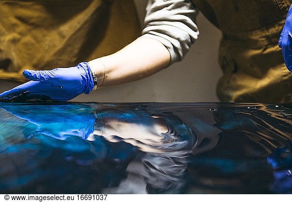 Detail einer Harzkünstlerin  die mit ihren Händen an einem großen Kunstwerk arbeitet