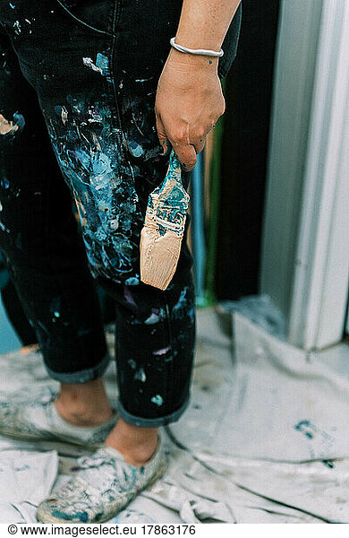 detail of a paint covered pant leg and paint brush
