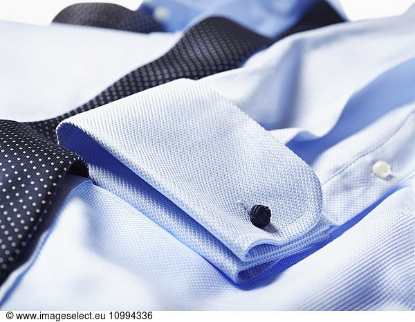 Detail of cuff of blue shirt with tie over in studio