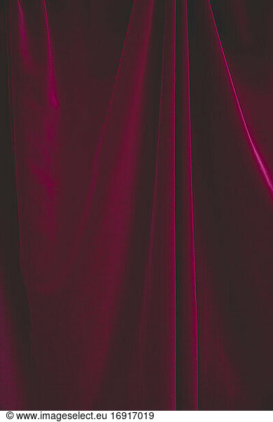 Detail of draped red velvet curtain with folds and creases