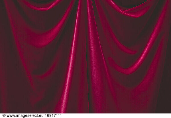 Detail of draped red velvet curtain with folds and creases