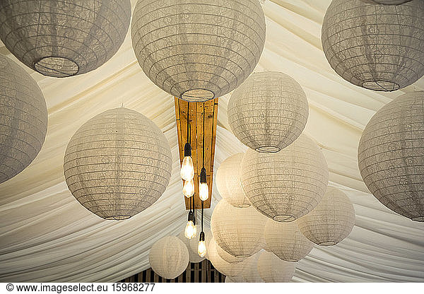 Detail of white Japanese Rice Paper lamps and fabric canopy  decorations for a naming ceremony in an historic barn.