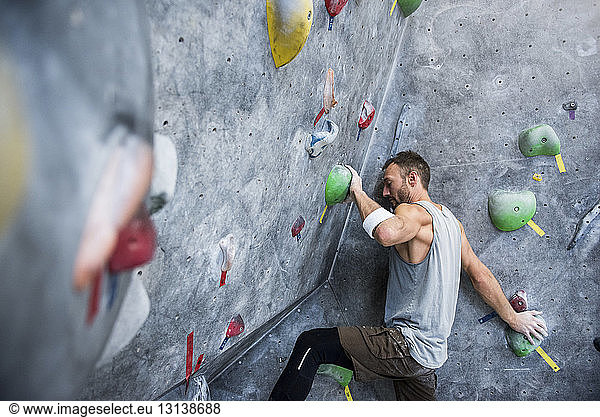 Determined athlete climbing on rock wall at gym