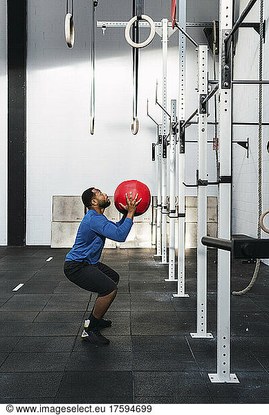 Determined athlete exercising with medicine ball in crossfit gym
