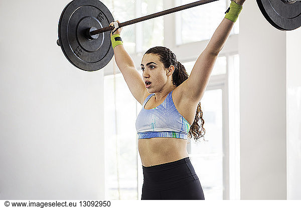 Determined athlete lifting barbell in crossfit gym