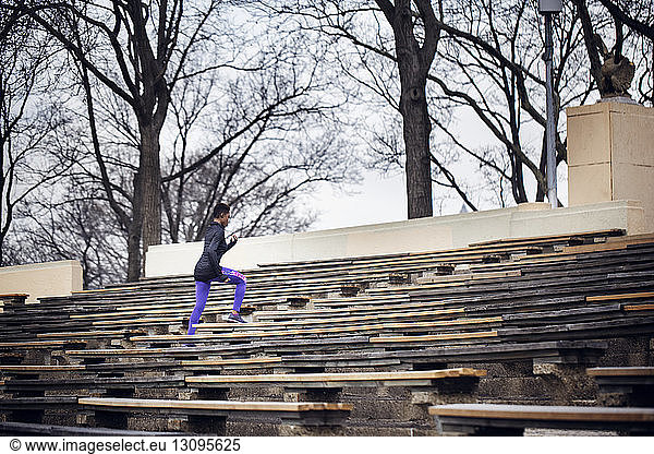 Determined female athlete running on amidst benches at stadium