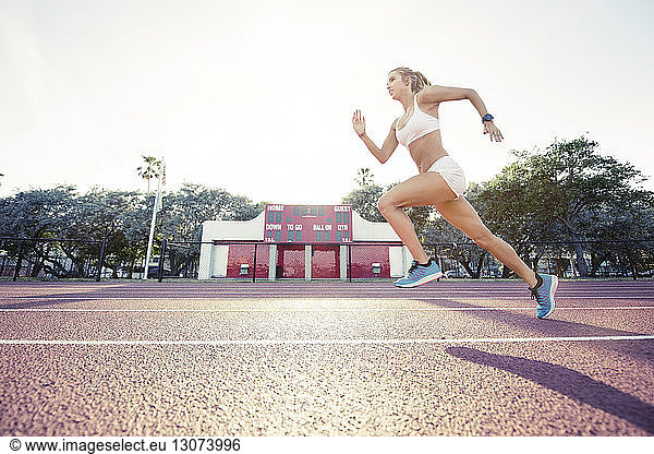 Determined female athlete running on race track