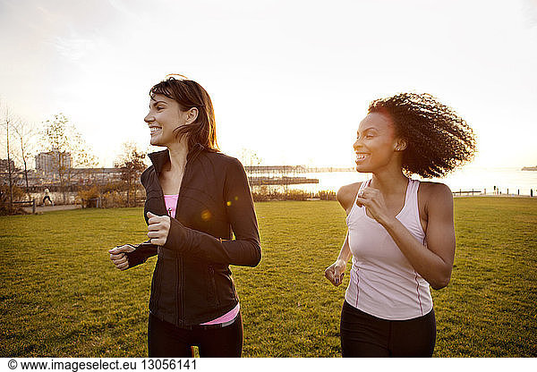Determined female friends jogging at park against clear sky