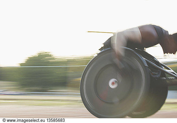Determined male paraplegic athlete speeding along sports track in wheelchair race