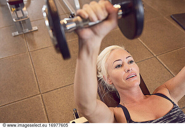 Determined sportive woman exercising with dumbbells
