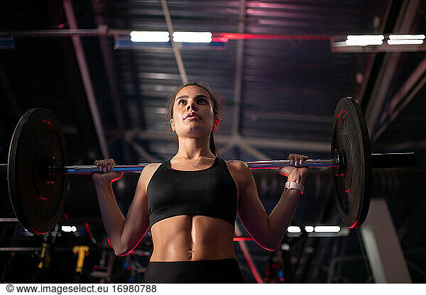 Determined sportswoman with barbell in gym