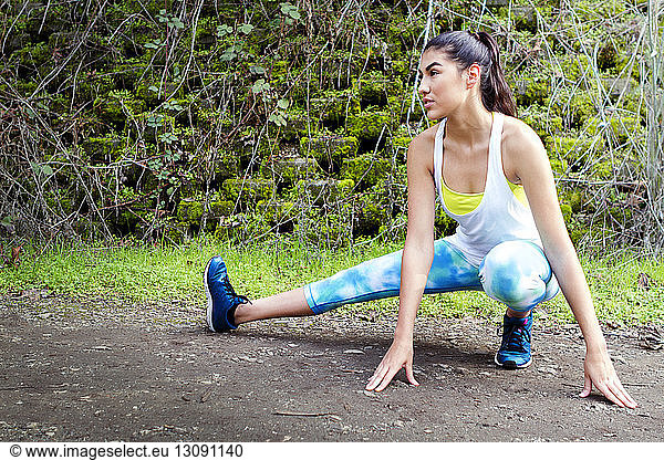 Determined sporty woman stretching on field